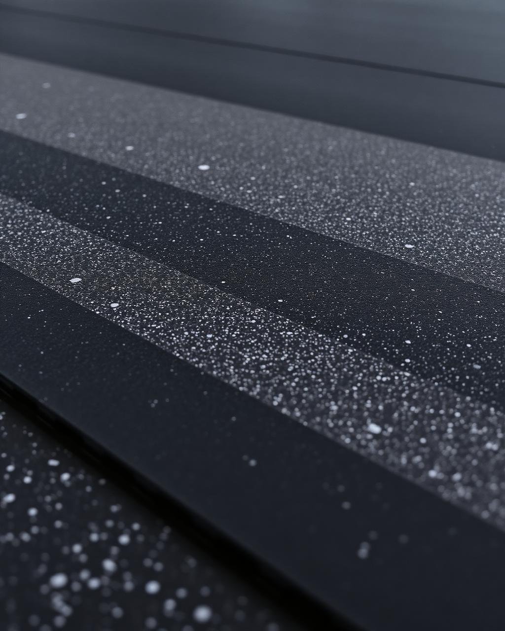 Macro of charcoal rubber gym flooring tile with grey speckle and interlocking edge