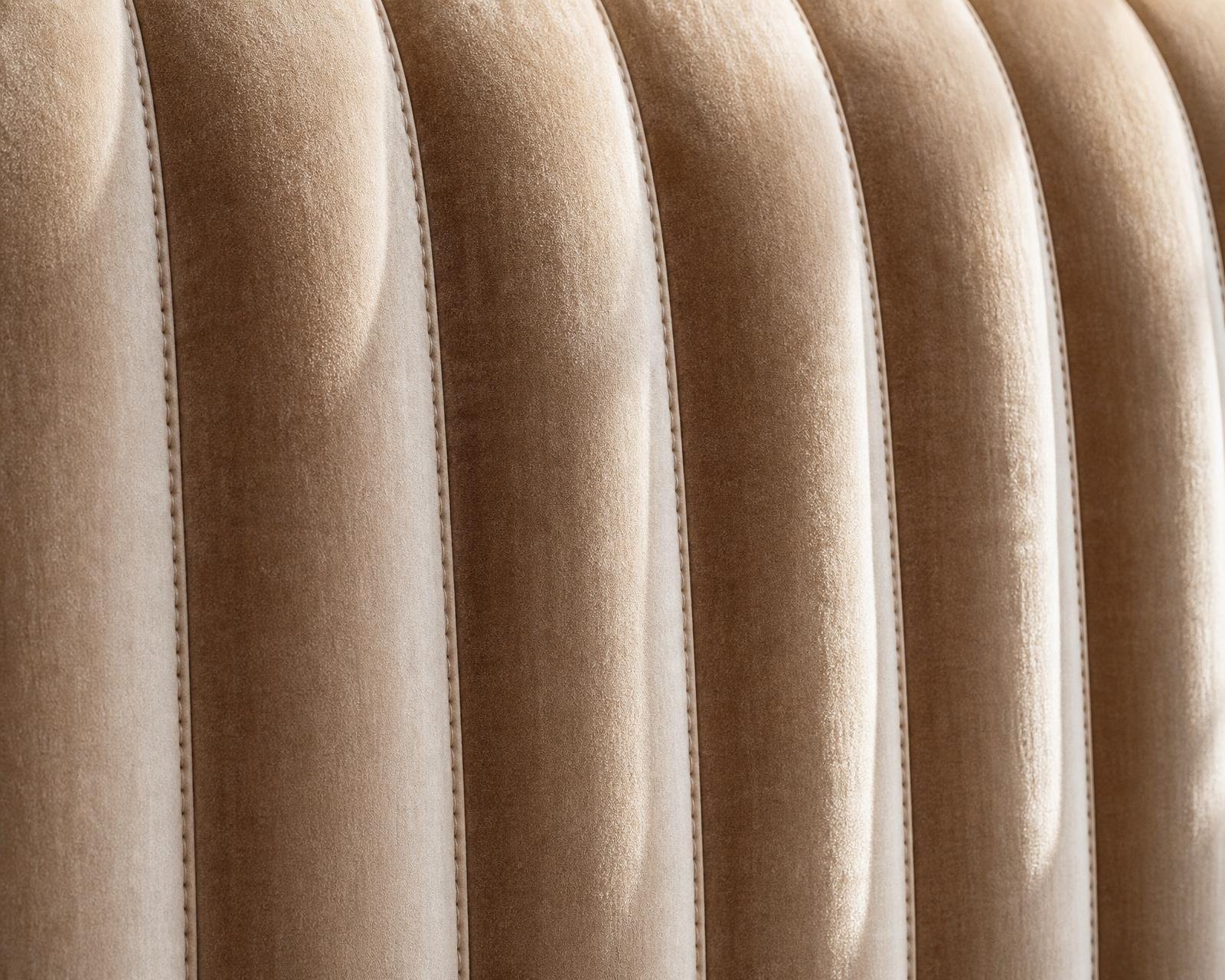 Macro of champagne velvet headboard with vertical channel tufting and hand-stitched seams