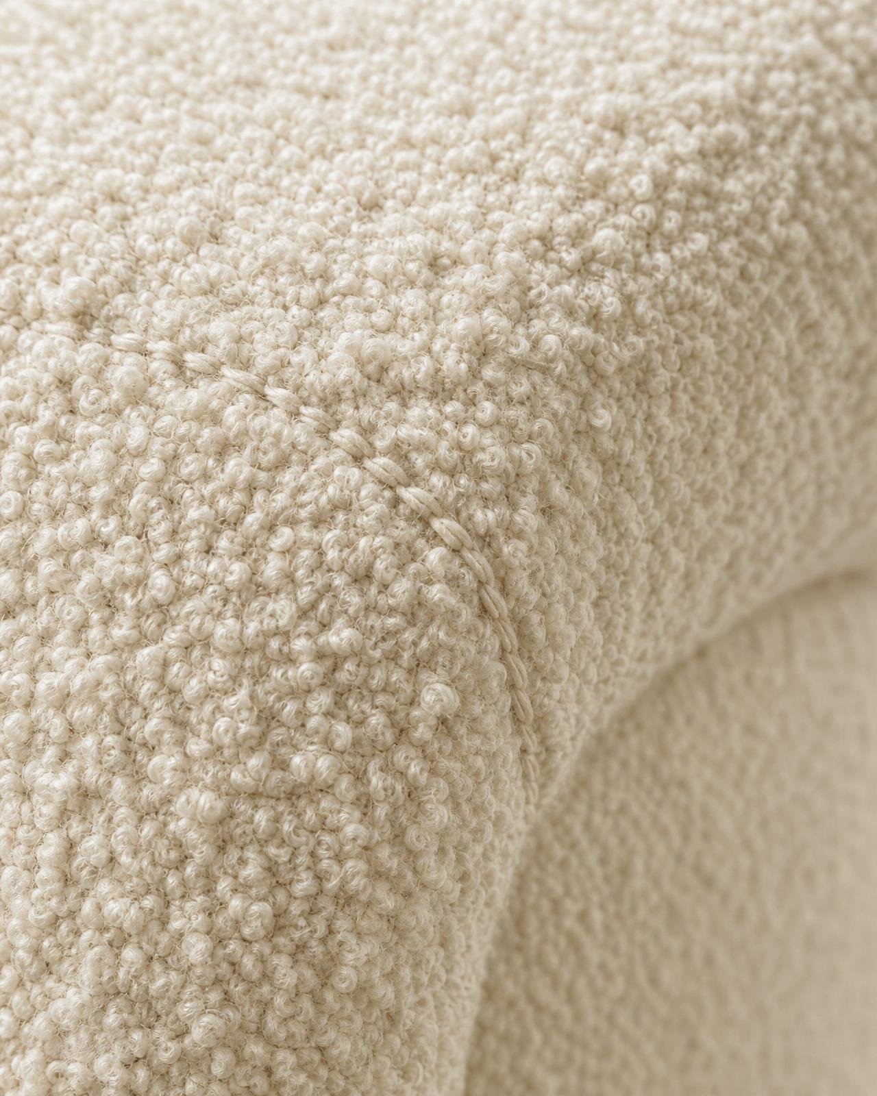 Macro of plush ivory bouclé upholstery with visible loops and seam detail